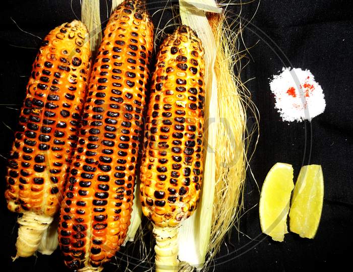 Grilled sweet corn garnished with spicy salt and lemon