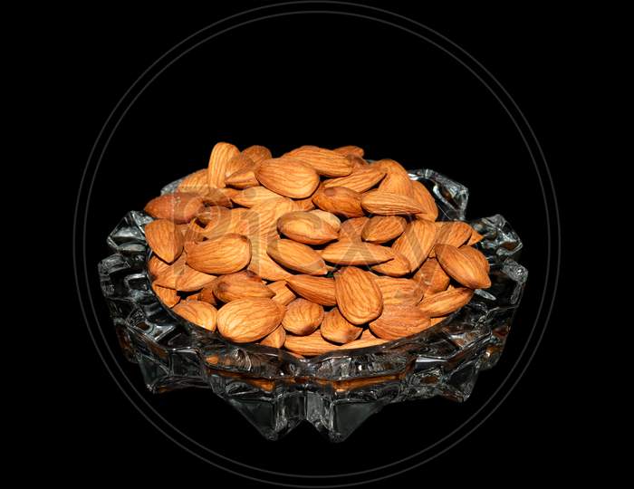 Almond nuts on a glass tray isolated on black background