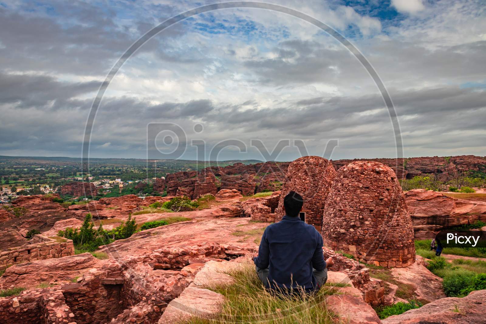 Man Meditating At Mountain Top With Ruins Of Historical Fort In The Background At Morning