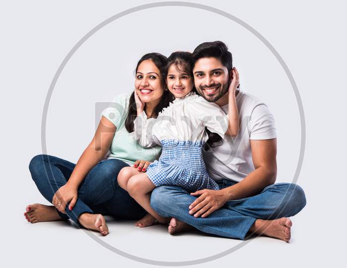 Portrait Of Young Indian Family Of Four Looking At Camera On White Background