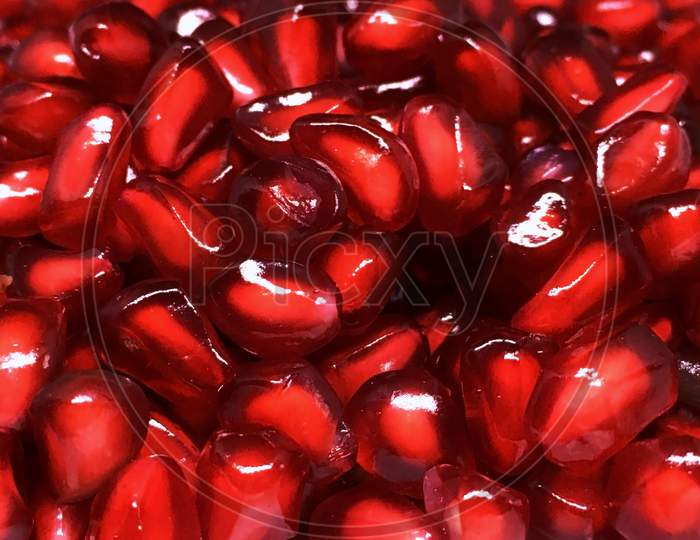 Fresh red pomegranate seeds stack background