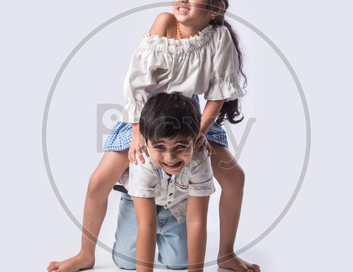 Two Happy Excited Indian Kids Having Fun, Riding On The Back At Home