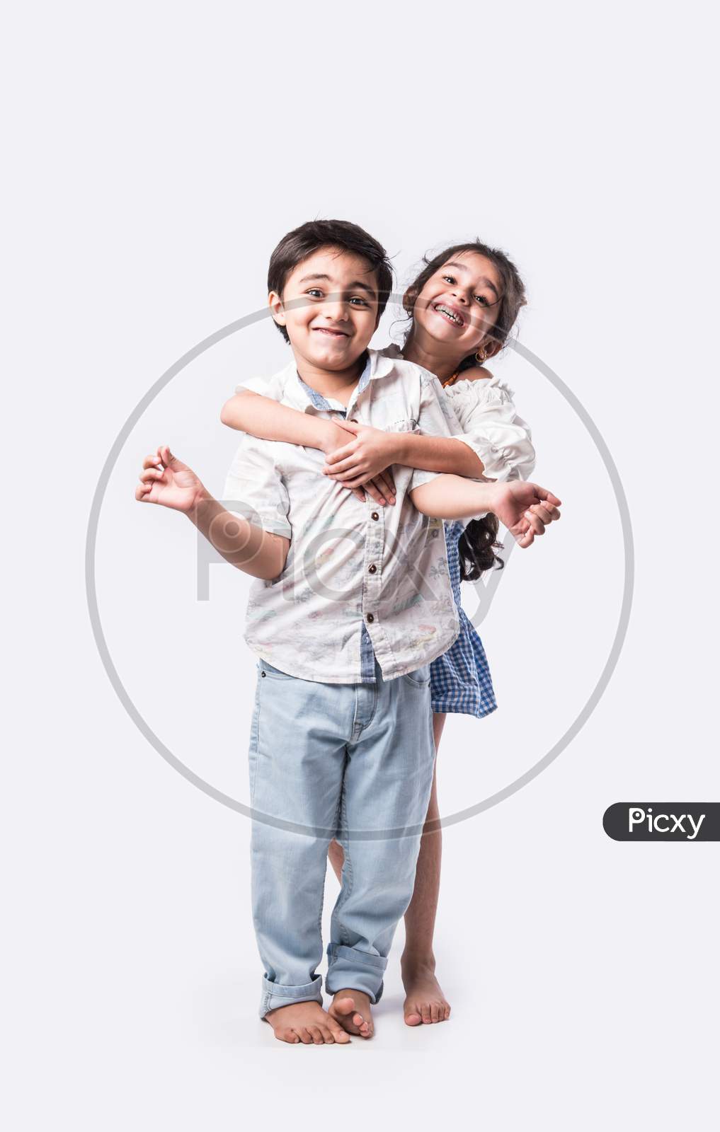 Indian Asian Cute Little Siblings Embracing While Wearing White Cloths Against White Background