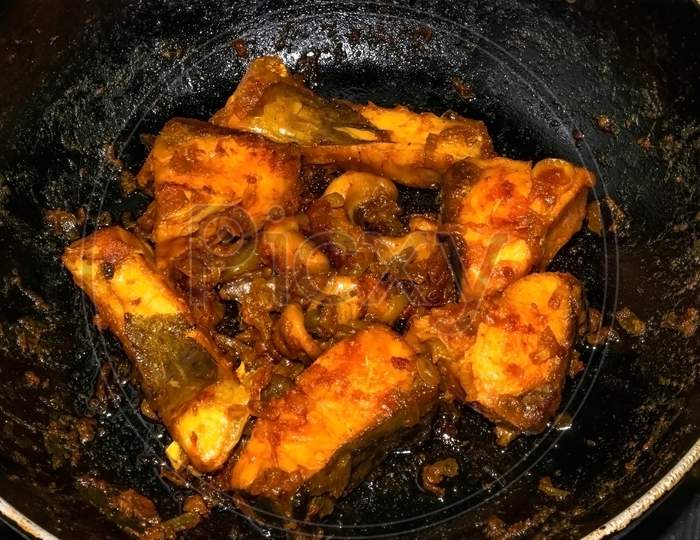 Preparation of spicy Indian fish dish on frying pan