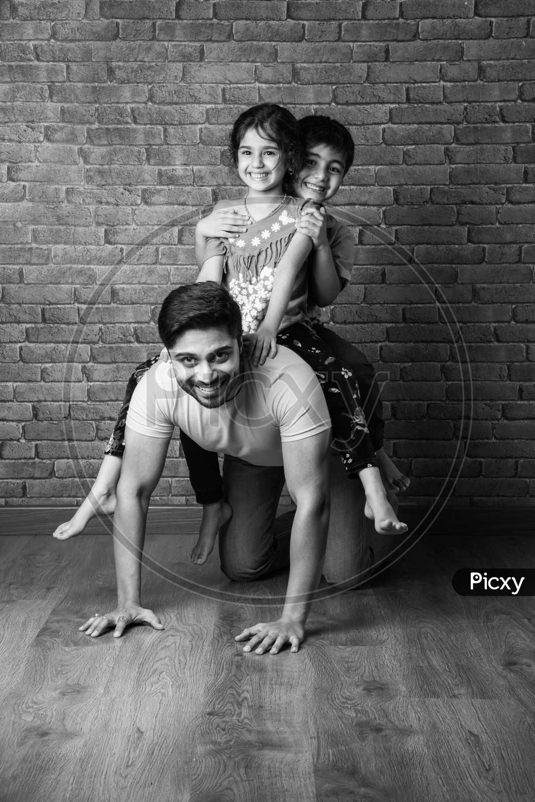 Happy Indian Girl And Boy Playing Riding On Back Or Piggyback With Father