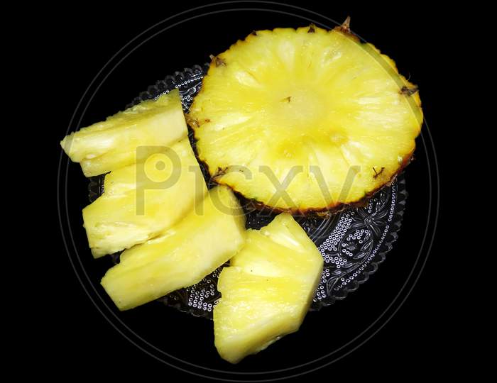 Sliced pineapple served for eating on black background