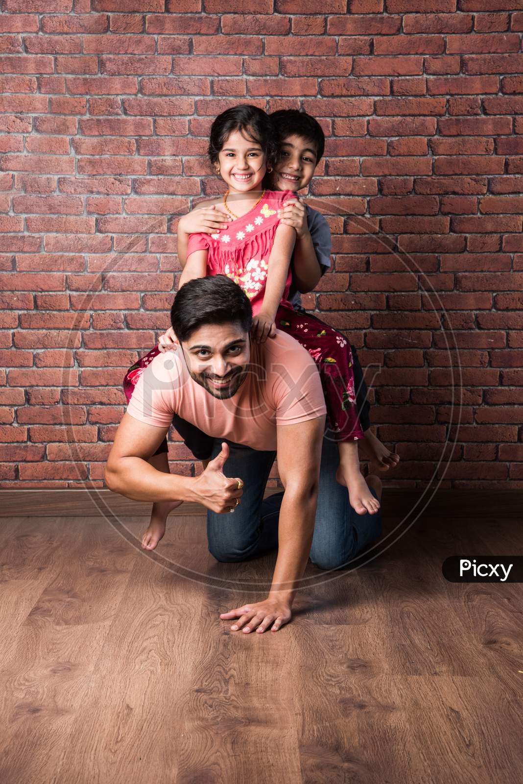 Happy Indian Girl And Boy Playing Riding On Back Or Piggyback With Father