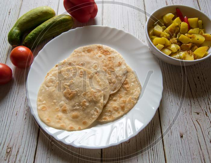 Paratha and cooked potatoes in a bowl along with condiments