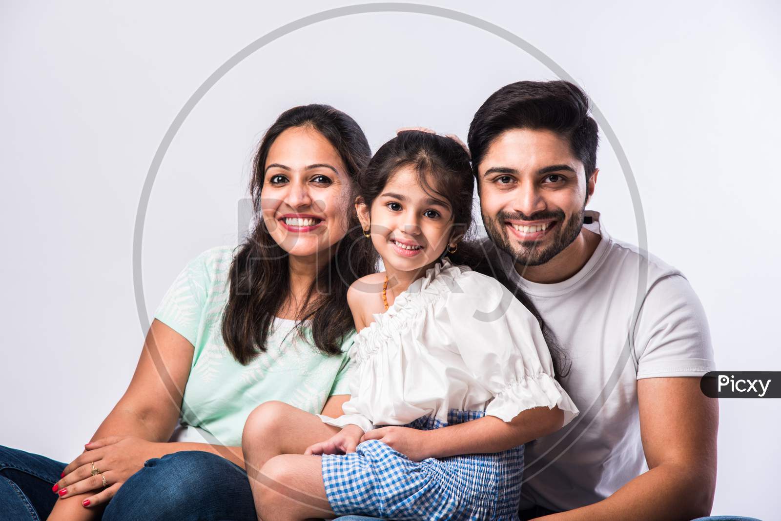 Portrait Of Young Indian Family Of Four Looking At Camera On White Background
