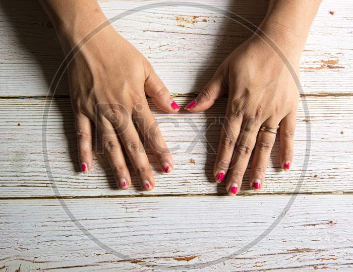 Chipped nail polish on the finger nails of a woman hands on a background.