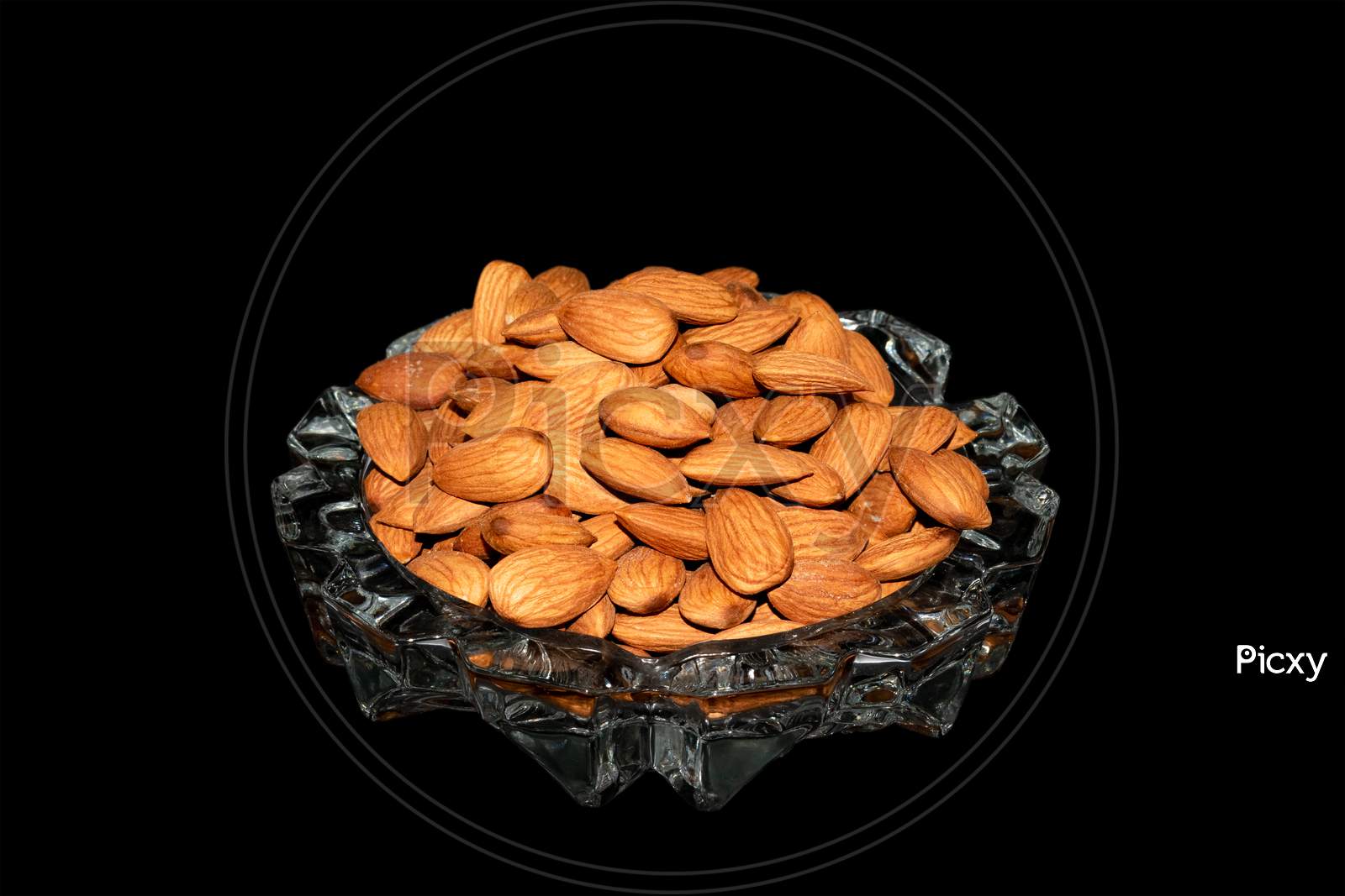 Almond nuts on a glass tray isolated on black background