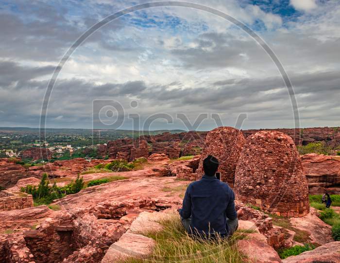 Man Meditating At Mountain Top With Ruins Of Historical Fort In The Background At Morning