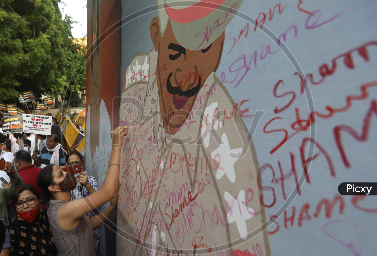 A demonstrator uses a lipstick to write on a billboard during a protest after the death of a rape victim, in New Delhi, India, October 2, 2020.
