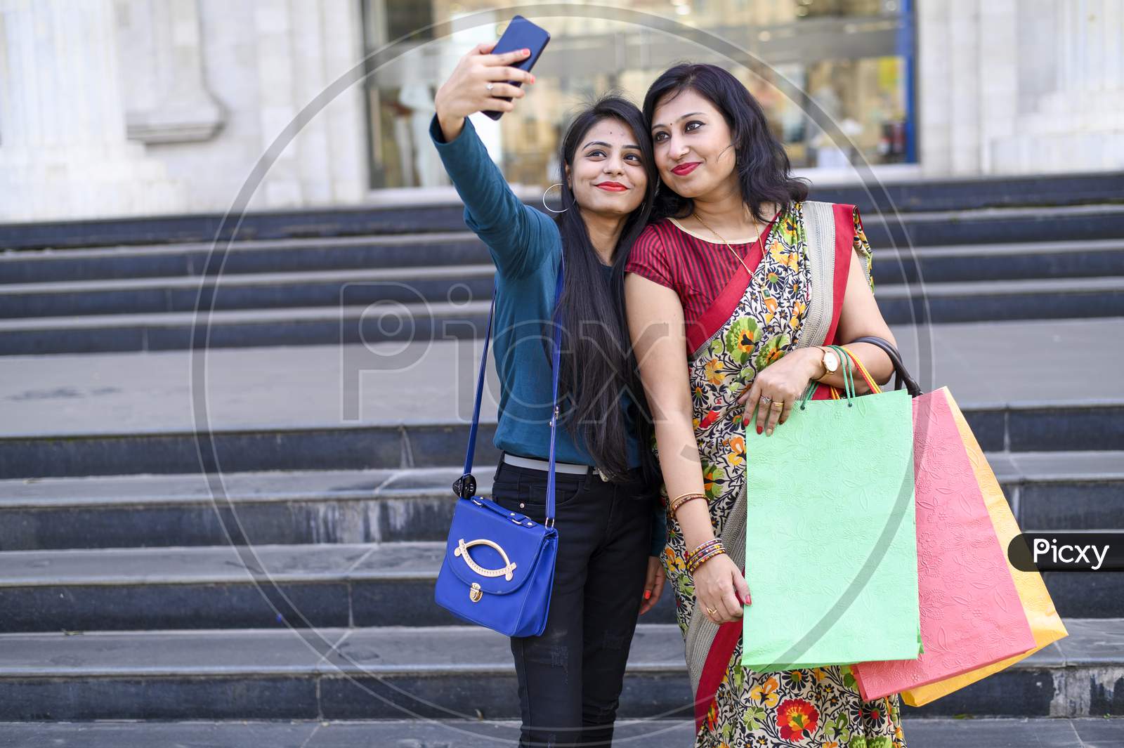 Mother and daughter are taking a selfie outdoor during a shopping day