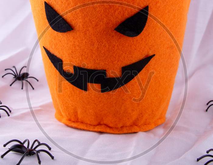 Halloween Fun For Kids Going Out To Trick Or Treat. Orange Pumpkin Candy Loot Bag In Circle Of Black Plastic Spiders