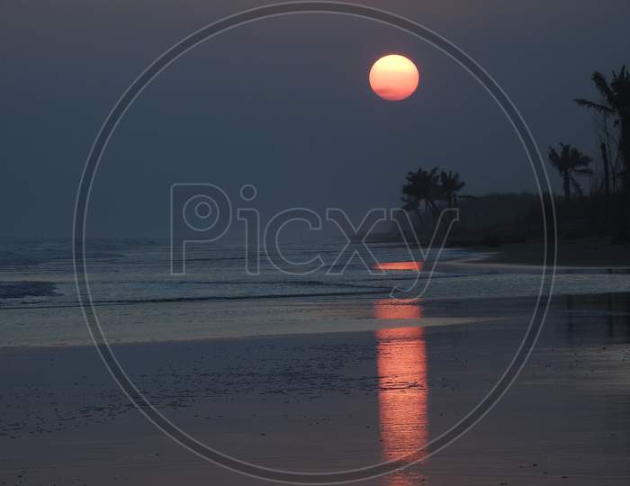 Reflection image of sun near a beach at sunset.