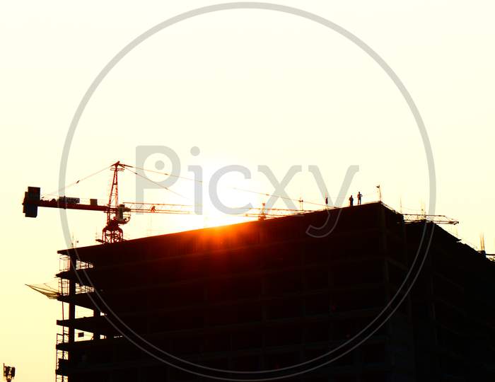 Silhouette engineer standing orders for construction crews to work on high ground heavy industry and safety concept over blurred natural background sunset pastel on horizon with tower crane