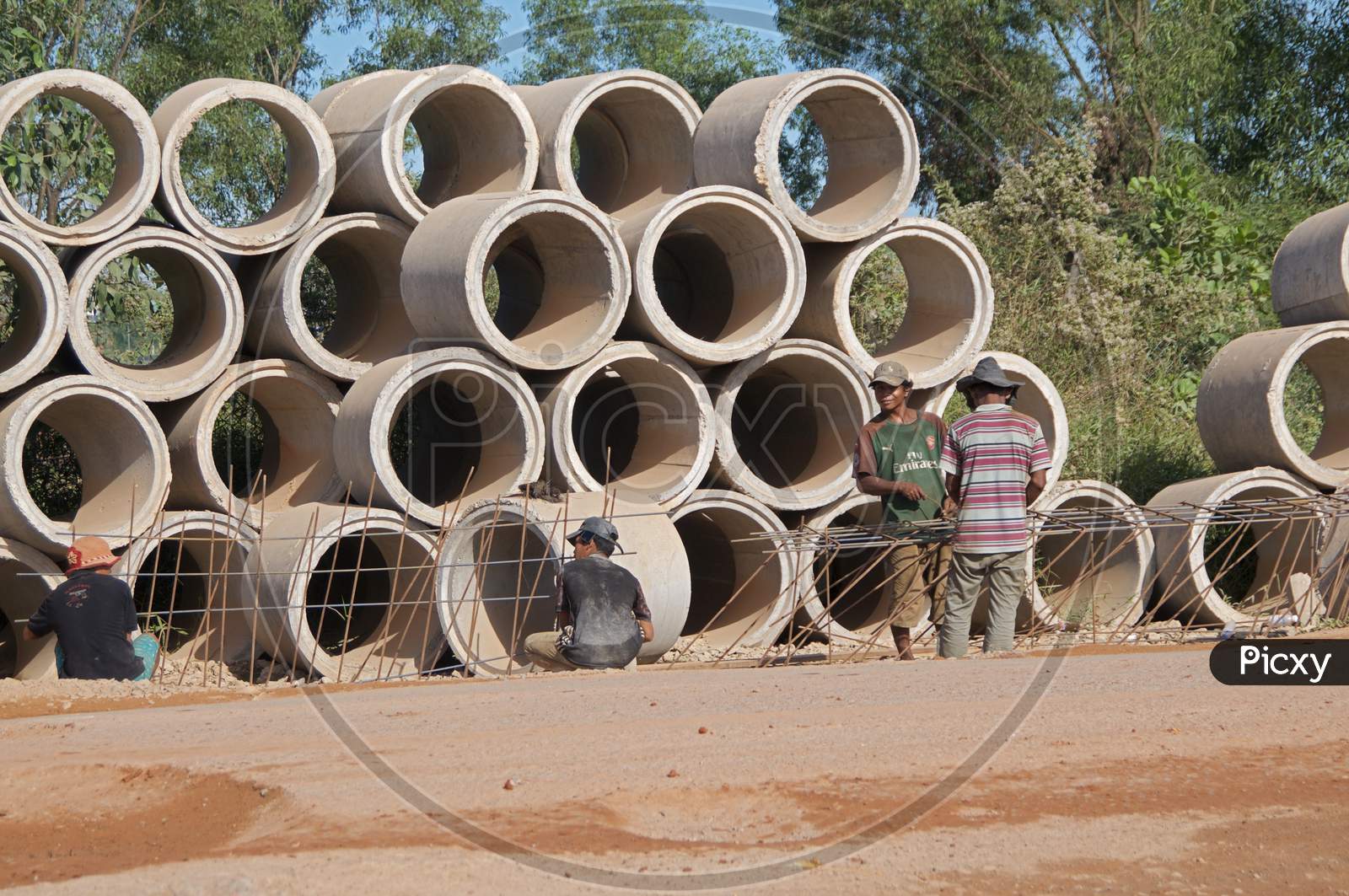 Cambodian Street Construction Site With Workers And Concrete Pipes
