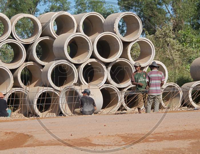 Cambodian Street Construction Site With Workers And Concrete Pipes