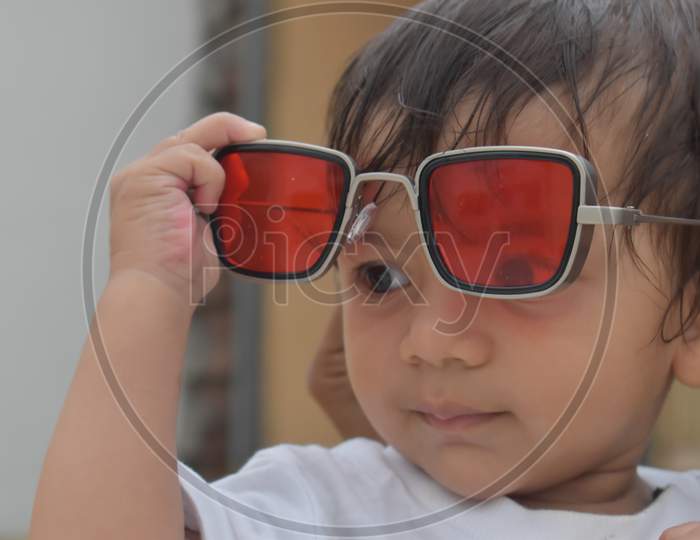 a photo of little boy holding hands red sunglasses