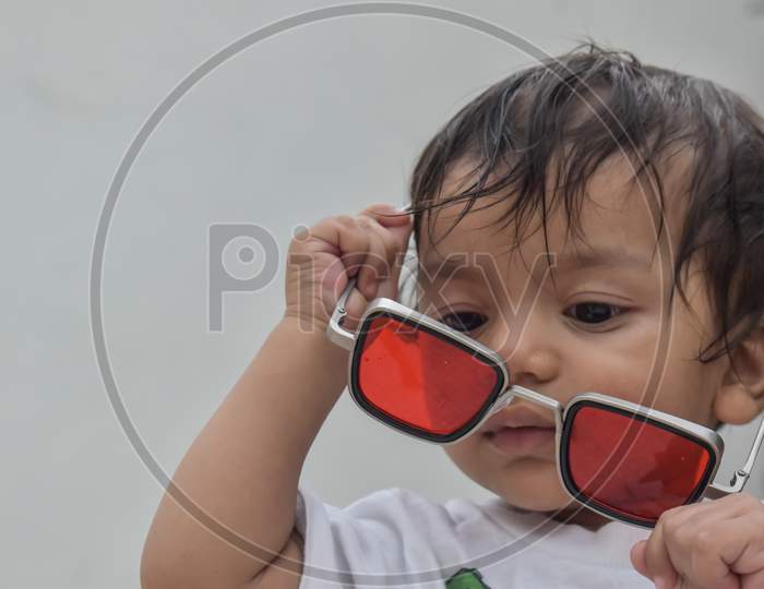 a little baby playing with red sunglasses