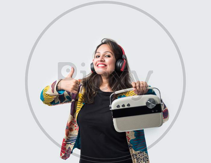 Indian Asian Young Woman Listening Music On Retro Style Radio With Headphones And Dancing