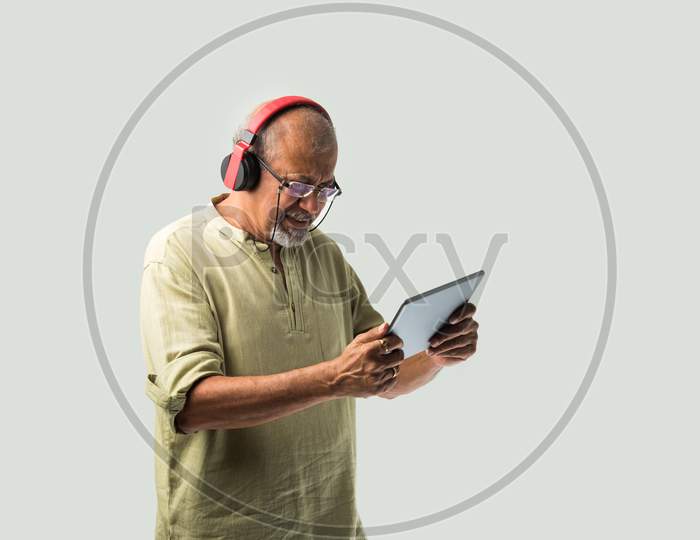 Indian Asian Senior Or Old Man Using Headphones With Smartphone Or Tablet, And Dancing