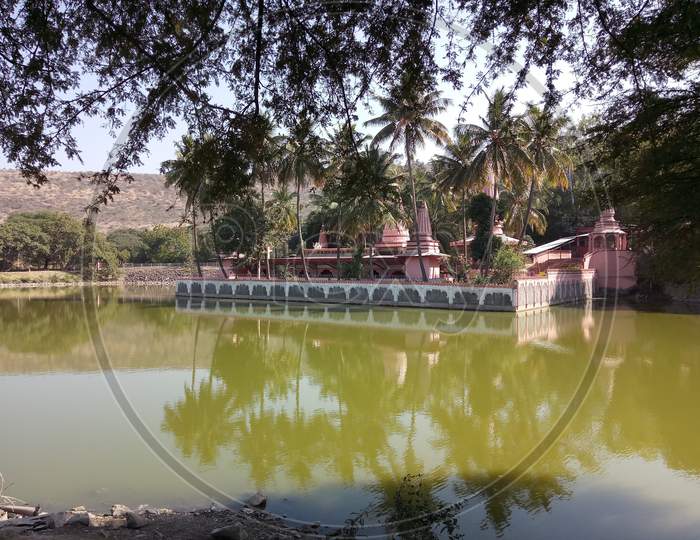 Beautiful temple reflection in a lake with greenray and coconut trees