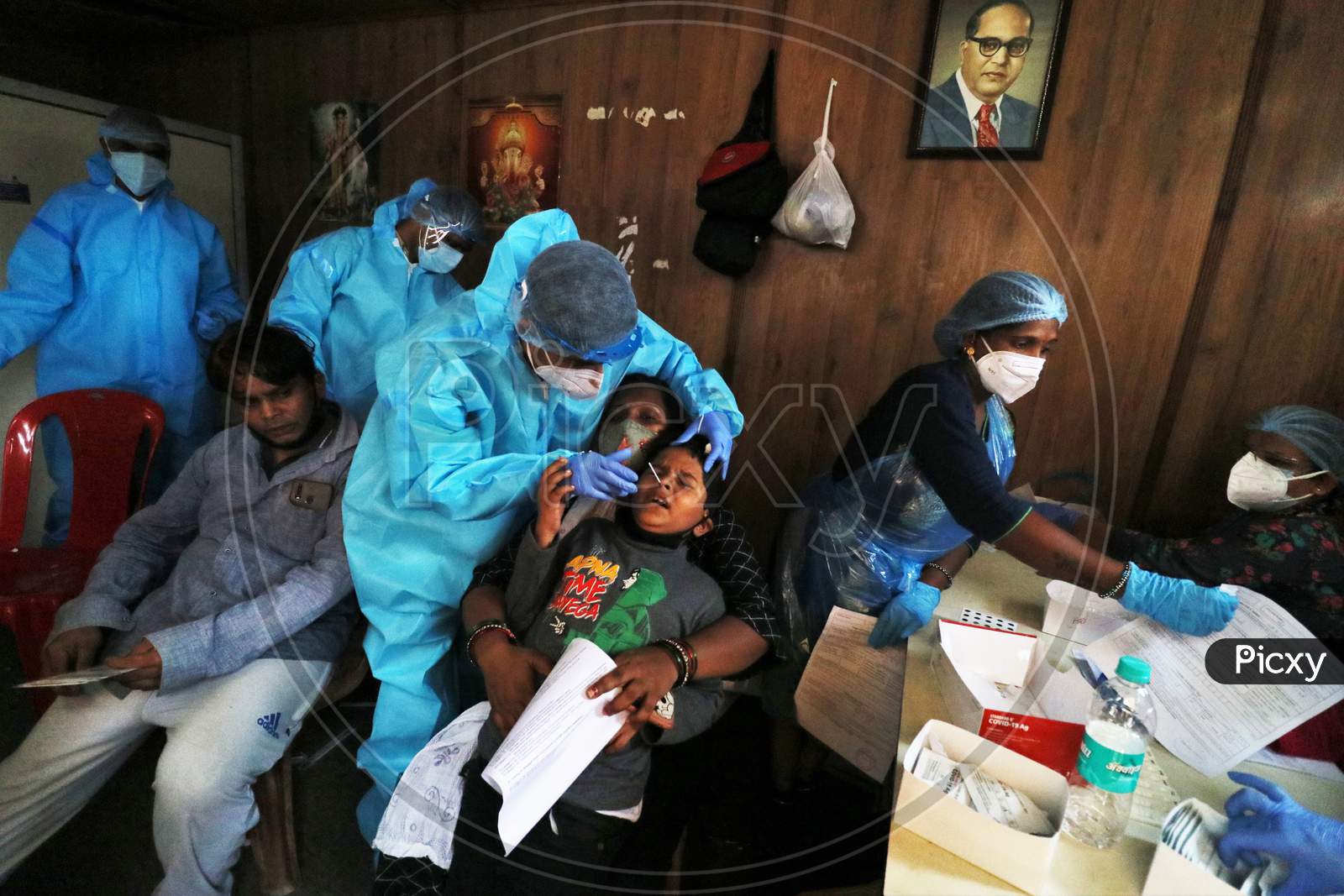 Health workers in personal protective equipment (PPE) collect swab samples from migrants who returned from their village at a railway station during a rapid antigen testing campaign for the coronavirus disease (COVID-19), in Mumbai, India, October, 2020.