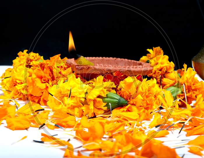 Marigold Flowers Around Clay Oil Lamp Or Diwali Diya, Over White Background. Selective Focus
