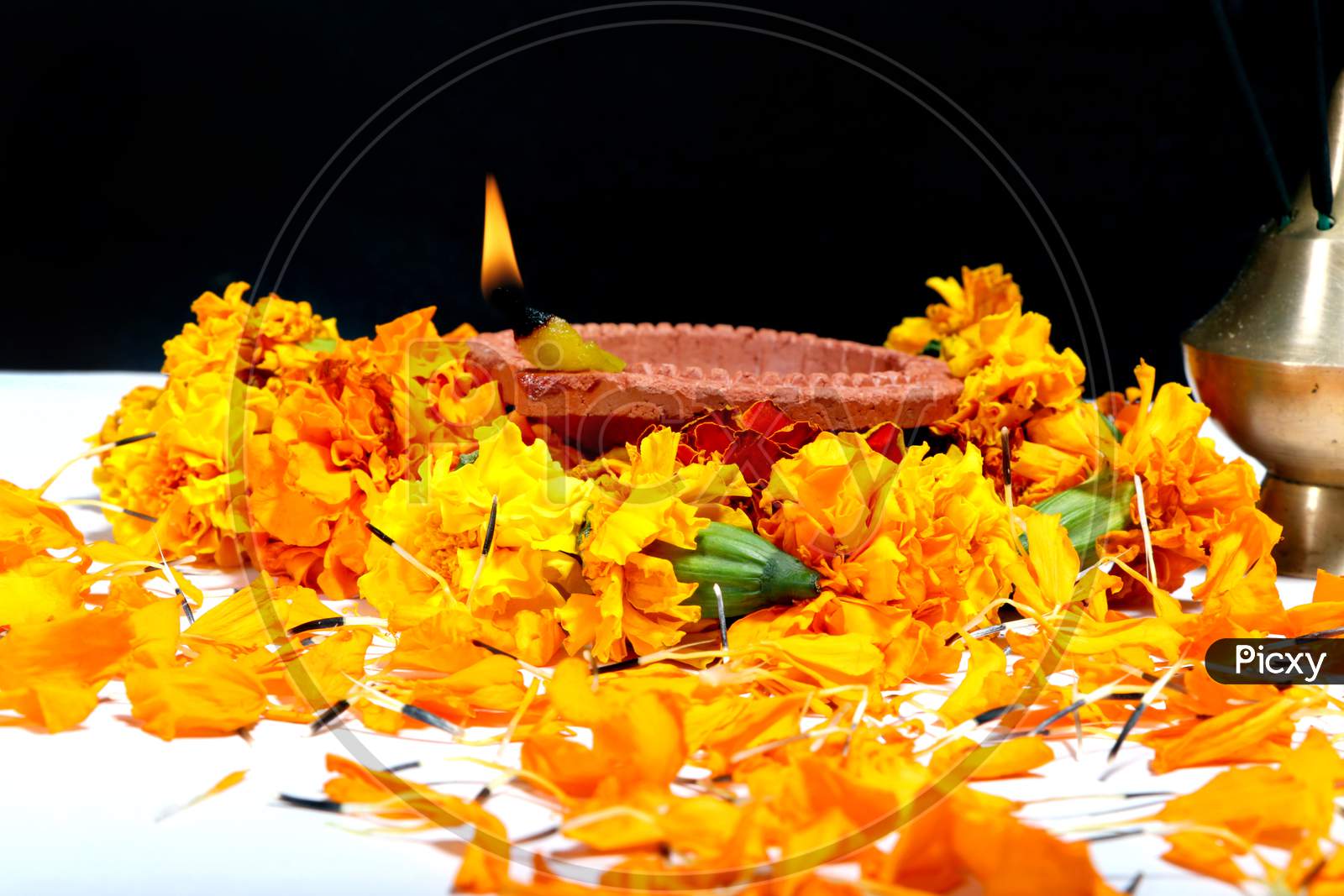 Marigold Flowers Around Clay Oil Lamp Or Diwali Diya, Over White Background. Selective Focus