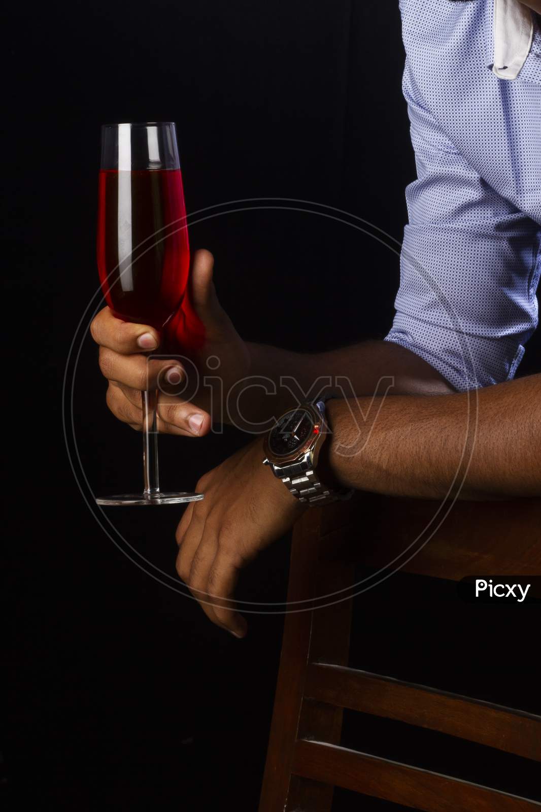 A Glass Of Red Wine With A Fireplace. Hand Holding Glass.