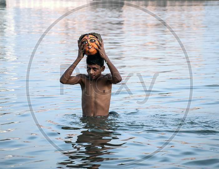 A boy collect a head of Devi Durga from the river Ganga.