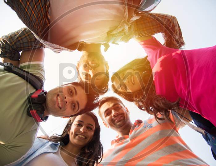 Indian Asian Cheerful College Students Forming A Circle And Looking Down At Camera