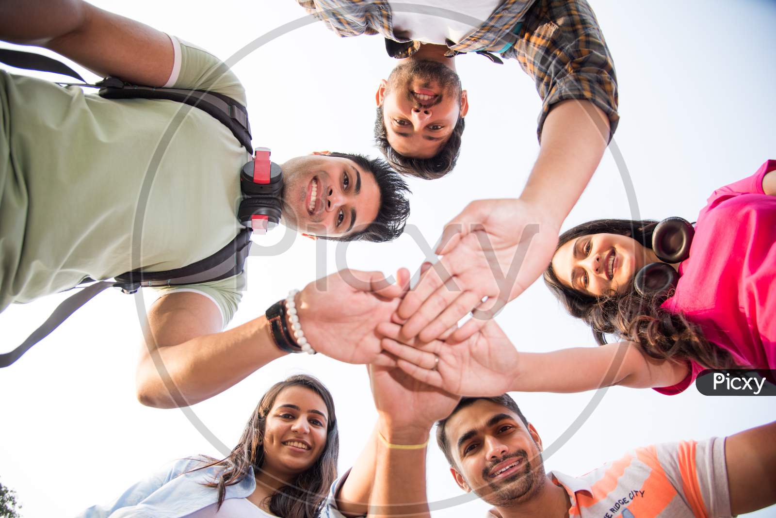Indian Asian Cheerful College Students Forming A Circle And Looking Down At Camera