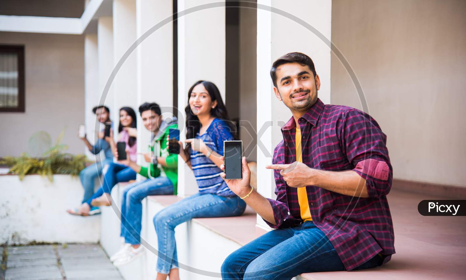 Indian Asian Group Of College Students Using Smartphones For Social Media, Texting, Watching Videos