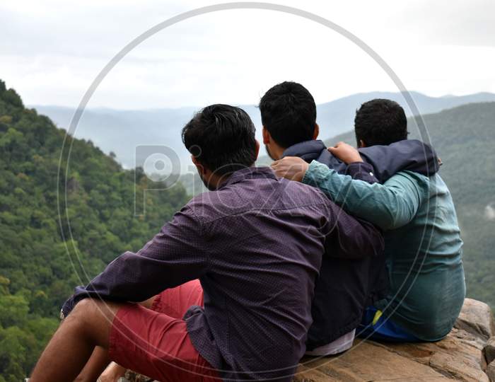 Three boys sitting at top of mountain