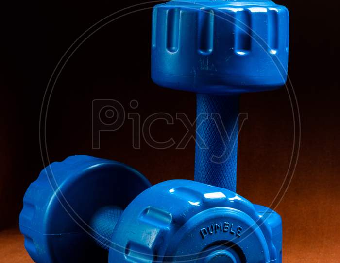 A Pair Of Blue Dumbbells Kept On A Table