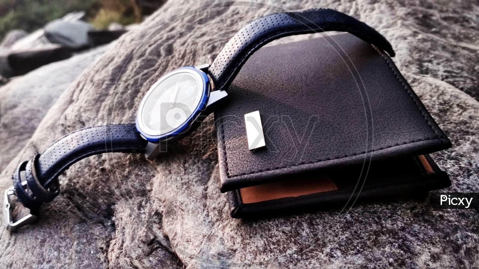 Closeup Shot Of A Watch And A Wallet On A Rock