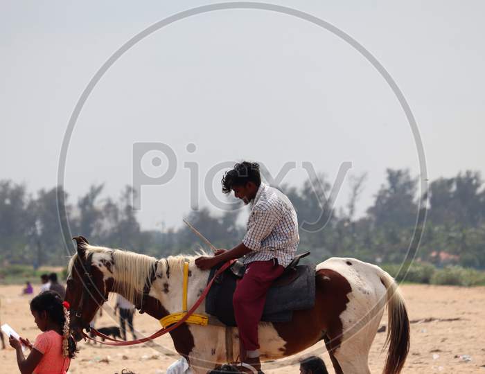 A Young Boy Riding A Horse In A Scenic Spot In India, Holding A Wooden Stick In His Hand