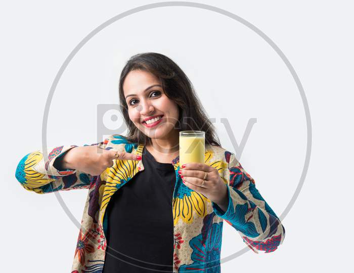 Asian Indian Pretty Girl Drinking Turmeric Milk In A Glass