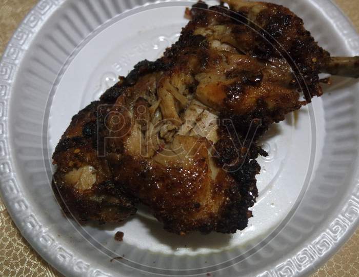 Close Up Of Roasted Chicken Pieces In A White Plate Served For Meal