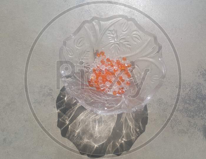 Shining, Transparent, Orange Color Crystal Beads Or Gemstones In A Glass Bowl