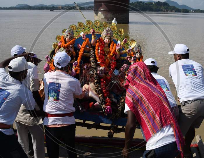 Municipal workers immerse an idol of the Hindu goddess Durga in the waters of the river Brahmaputra on the last day of the Durga Puja festival in Guwahati on Oct 26,2020.