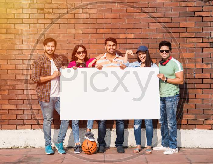 Indian Asian Group Of College Students Holding, Showing Blank White Placard, Board With Copy Space