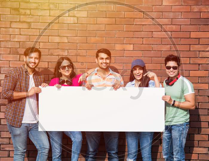 Indian Asian Group Of College Students Holding, Showing Blank White Placard, Board With Copy Space