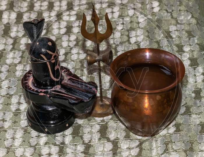 Hindu God lord Shiva linga Mahadeva with his sacred trident and snake and brass pot containing holy water