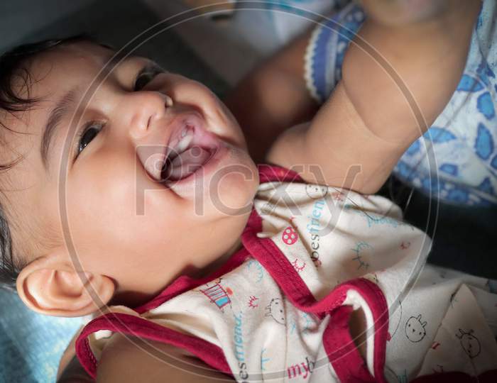 A Toddler Indian Baby Boy Smiling With First Tooth Visible On Upper Jaw With Selective Focus On Eyes