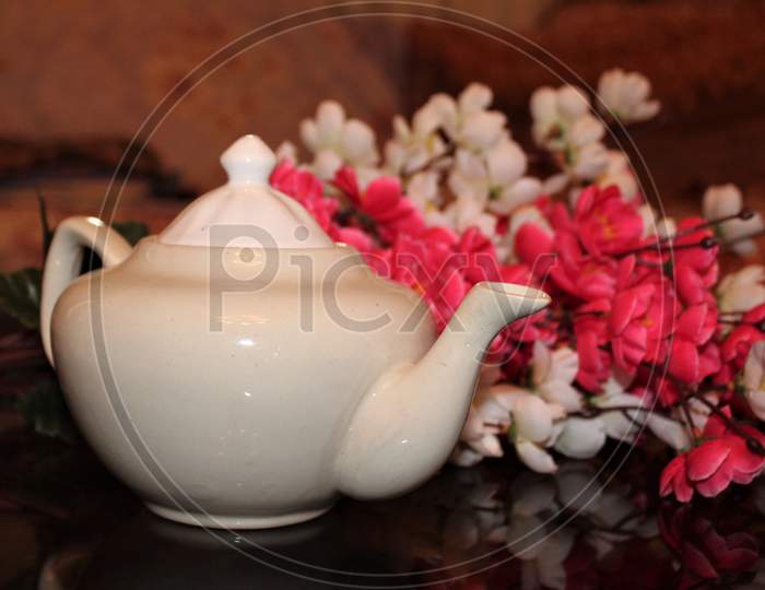 This picture shows a white tea pot with pink flowers