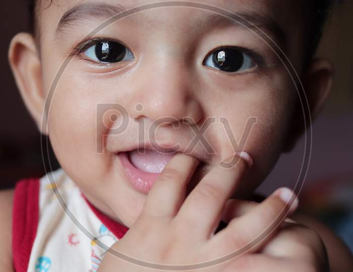 A Head Shot Vertical Portrait Of An Adorable Indian Baby Looking At The Camera With Selective Focus On Eyes
